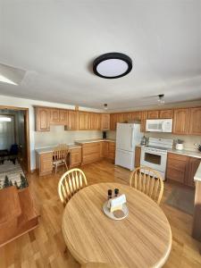 a kitchen with a table and chairs and a white refrigerator at UPTA CAMP LIMIT 8 cabin in West Baldwin
