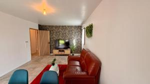 a living room with a leather couch and a television at Le Terrier in Noisiel