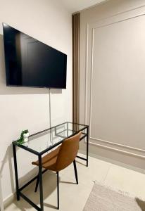 a glass table with a chair and a television on a wall at Orchid Belvedere Suites 102 - The Fig in Gaborone
