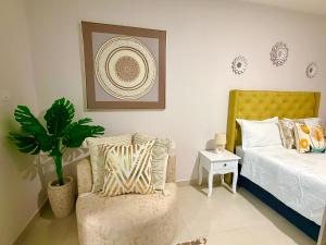 a bedroom with a bed and a chair and a plant at Orchid Belvedere Suites 102 - The Fig in Gaborone +21 photos
