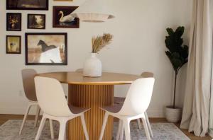 a dining room with a wooden table and white chairs at Brùn House in Fort Saint John