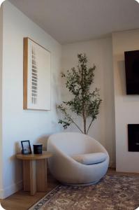 a white chair in a room with a tree at Brùn House in Fort Saint John