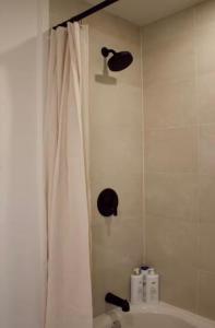 a bathroom with a shower with a white shower curtain at Brùn House in Fort Saint John