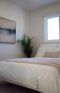 a white bedroom with a large bed and a window at Brùn House in Fort Saint John