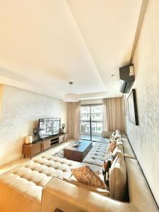 a large living room with a couch and a tv at Spacious Studio with Pool & Wi-Fi in Aïn Harrouda