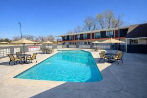 a swimming pool with tables and chairs and a building at Americas Best Value Inn Ponca City in Ponca City
