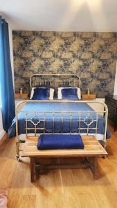 a bed with blue pillows and a bench in a room at Le Clos des Souvenirs in Étretat