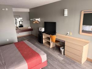 a hotel room with a bed and a desk with a television at Red Carpet Inn And Suites in Maple Shade