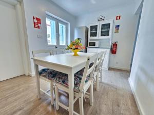 a white dining room table with chairs and a vase of flowers at Friends Place in Praia da Vitória