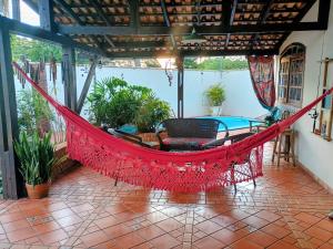 a red hammock on a porch with a pool at Casa Conforto & Lazer Foz do Iguaçu in Foz do Iguaçu