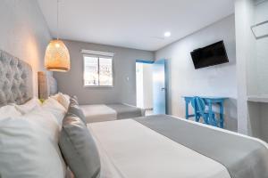 a bedroom with a large white bed and a television at Hotel Adaz Mediterráneo in Santa Marta