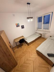 a room with two beds and a table and a desk at Zamkowy Hostel Gdansk Old Town in Gdańsk