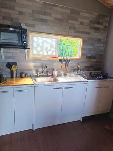 a kitchen with white cabinets and a sink and a window at Tu Refugio Quellon in Quellón