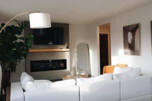 a living room with two white couches and a fireplace at Soleil House in Fort Saint John