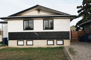 a white and black house with four windows at Soleil House in Fort Saint John
