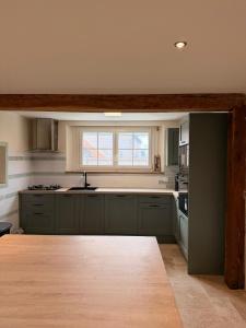 a kitchen with green cabinets and a window at Escale à Rosay in Theuville