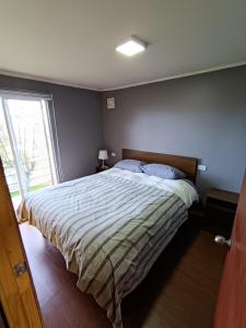 a bedroom with a large bed and a window at Tu Refugio Quellon in Quellón