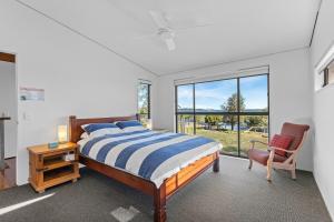 a bedroom with a bed and a chair and a window at Pindimar Beach Sanctuary Absolute Beachfront in Pindimar
