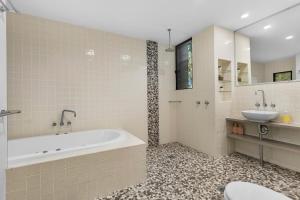 a bathroom with a tub and a sink and a toilet at Pindimar Beach Sanctuary Absolute Beachfront in Pindimar +58 photos