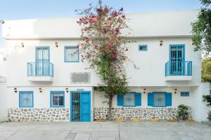 a white building with blue doors and a tree with flowers at Hotel Adaz Mediterráneo in Santa Marta +27 photos