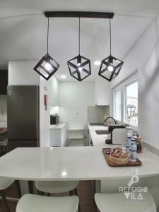 a kitchen with a white counter top and some lights at Refúgio da Vila in Vila de Rei