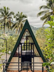 a triangular building with a window and palm trees at Sunshine Cabana and Resort in Haldummulla