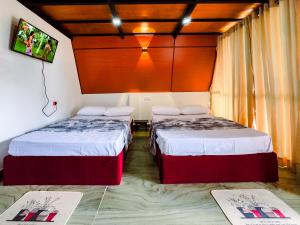 a room with two beds and a tv on the wall at Sunshine Cabana and Resort in Haldummulla +5 photos