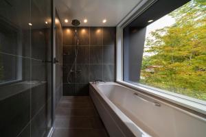 a bathroom with a bath tub and a window at Chalet Infinity in Hakuba +36 photos