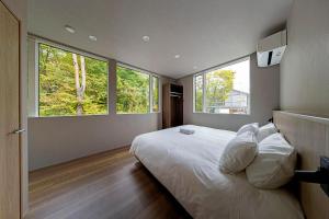 a bedroom with a large bed with two large windows at Chalet Infinity in Hakuba