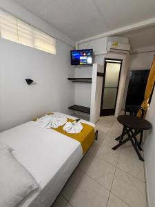 a bedroom with a bed and a table and a tv at Hotel SR, Villa Garzón in Villagarzón