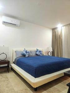 a bedroom with a large bed with blue sheets at Cancún Arbolada Huayacan in Cancún
