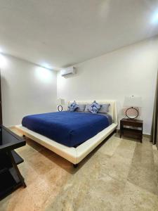 a bedroom with a bed with a blue comforter at Cancún Arbolada Huayacan in Cancún +29 photos