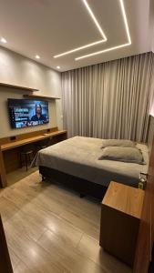 a bedroom with a bed and a flat screen tv at Pousada das Águas in Lambari
