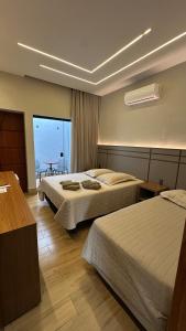 a hotel room with two beds and a table at Pousada das Águas in Lambari