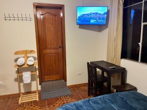 a room with a bed and a television on the wall at Granja Doña Carmelita in Ibarra