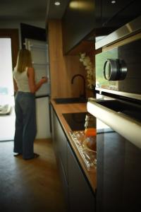 a woman standing in a kitchen looking into a refrigerator at Villa San Martino in San-Martino-di-Lota
