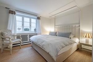 a white bedroom with a large bed and a chair at Deichgraf 4 in Kampen