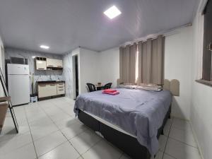 a bedroom with a large bed and a kitchen at Studio luxo Periperi in Salvador