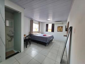 a bedroom with a bed and a table and a bathroom at Studio luxo Periperi in Salvador