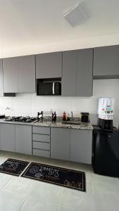 a kitchen with white cabinets and a black refrigerator at Doce Lar 2 in Pouso Alegre +16 photos