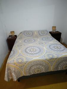 a bed with a quilt on it with two night stands at Tu alojamiento in Tacuarembó