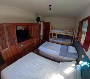 a small bedroom with two beds and a tv at Nuh Hostel - Quartos coletivos in Ouro Preto