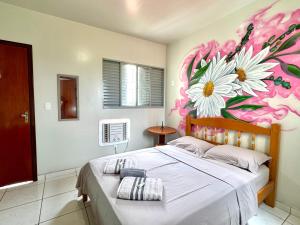 a bedroom with a bed with a flower mural on the wall at Casa Flora in Barra do Garças