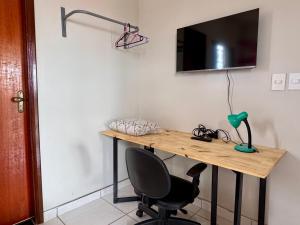 a desk with a chair and a television on a wall at Casa Flora in Barra do Garças