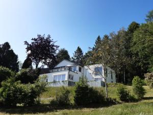 a white house on a hill with trees at Panoramic villa with private sauna in Érezée