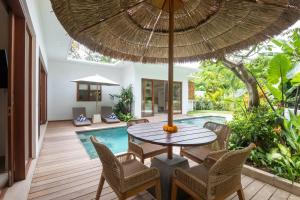 an outdoor dining area with a table and chairs and an umbrella at Villa Jacelyne - Tropical 2BR Villa with Private Pool in Canggu in Dalung