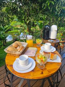 a table with a breakfast of bread and orange juice at Chalé Elemental in Morretes