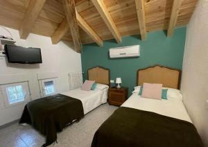 a bedroom with two beds and a tv on the wall at Villa Pachita (por habitaciones) in Alhama de Aragón