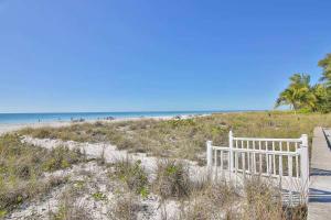 a white bench sitting on a sandy beach at 3B Beachfront Condo - Heated Pool & 18ft Balcony in Holmes Beach