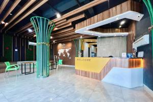 a lobby with green columns and a table and chairs at SANS Vibes Millenium Inn Medan in Pulauberayan